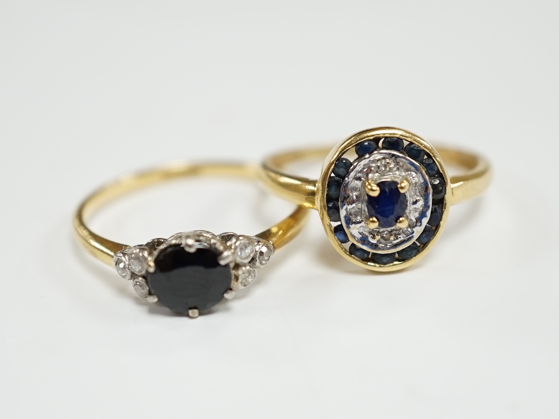 An 18ct, sapphire and diamond set seven stone ring, size P and a French 18k and sapphire set oval cluster ring, size O, gross weight 4.7 grams.